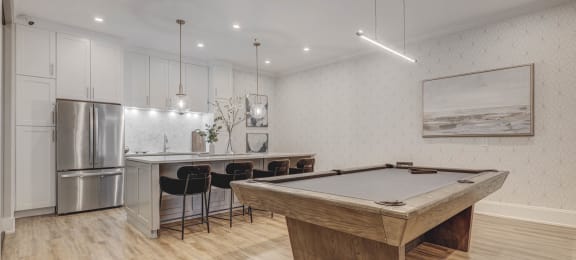 a game room with a pool table and a kitchen with stainless steel appliances