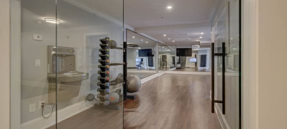 a home gym with a glass wall and hardwood flooring