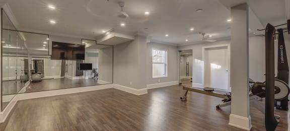 a spacious fitness room with hardwood flooring and a large mirror on the wall