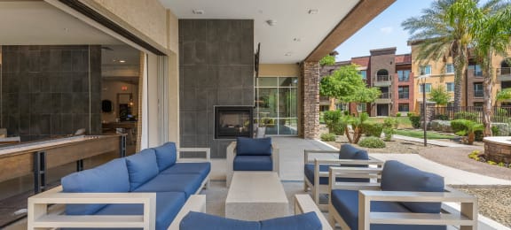 a patio with blue couches and chairs and a fireplace