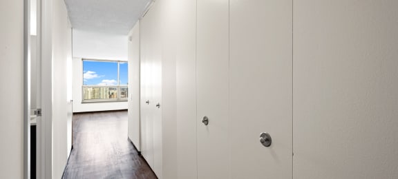 a hallway with white closets and a view of a window at Presidential Towers, Chicago, 60661