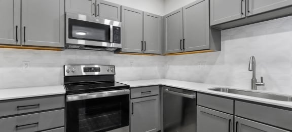 an empty kitchen with stainless steel appliances and white cabinets at Switchback on Platte Apartments, Littleton