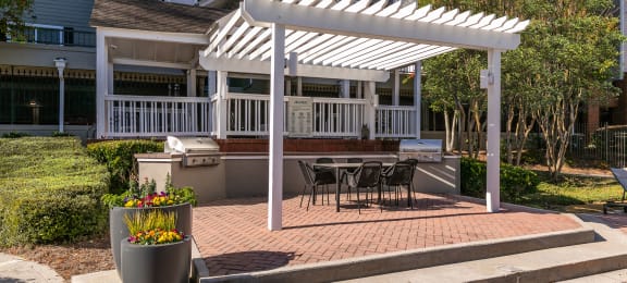 a white pergola on a brick patio with a table and chairs at Briarcliff Apartments, Georgia, 30329