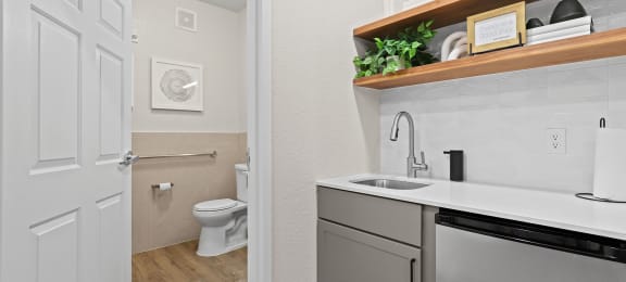 a bathroom with a sink and a toilet and a laundry room with a door open at Switchback on Platte Apartments, Littleton, CO 80120
