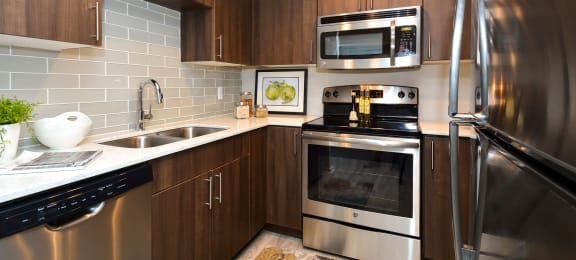 a kitchen with stainless steel appliances and wooden cabinets  at Apartments at Denver Place, Denver, 80202
