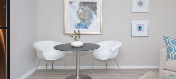 a dining room with a table and chairs and a painting on the wall  at Apartments at Denver Place, Denver, CO