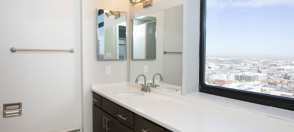a bathroom with a large window and a sink and mirror at Apartments at Denver Place, Colorado