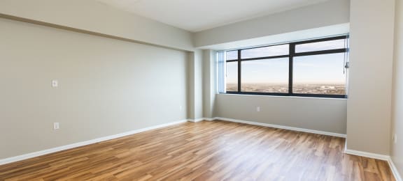 an empty living room with wood floors and a window at Apartments at Denver Place, Denver, CO
