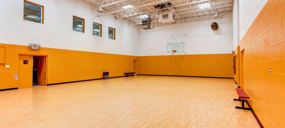 a large gym with a wooden floor and yellow and white walls at Willow Hill Apartments, Justice