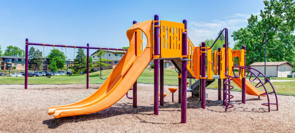 a playground with a yellow slide and other playground equipment at Willow Hill Apartments, Justice, IL