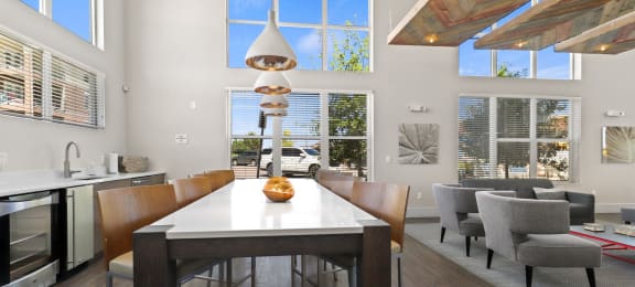 a dining area with a table and chairs and large windows at Ridge at Thornton Station Apartments, Colorado