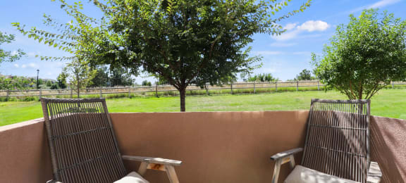 a patio with two chairs and a table and a tree at Ridge at Thornton Station Apartments, Thornton