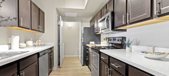 a large kitchen with stainless steel appliances and white counter tops at Ridge at Thornton Station Apartments, Thornton
