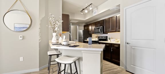 a kitchen with a bar and stools in a renovated apartment at Ridge at Thornton Station Apartments, Thornton, CO