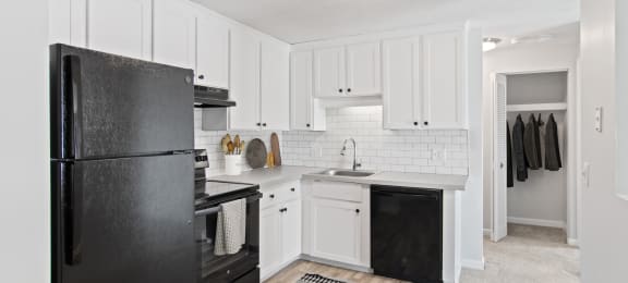 a renovated kitchen with black appliances and white cabinets  at Rosemont Square Apartments, Randolph