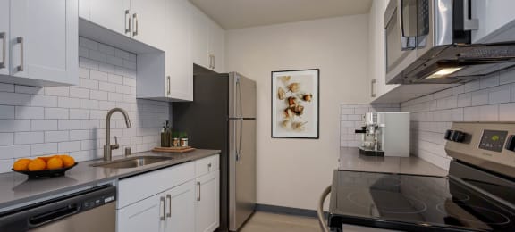 a kitchen with stainless steel appliances and white cabinets at Delphine on Diamond, California, 94131