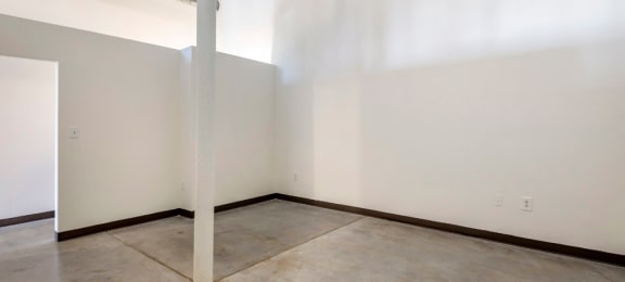 an empty room with white walls and a concrete floor and a pole at Highland Mill Lofts, North Carolina