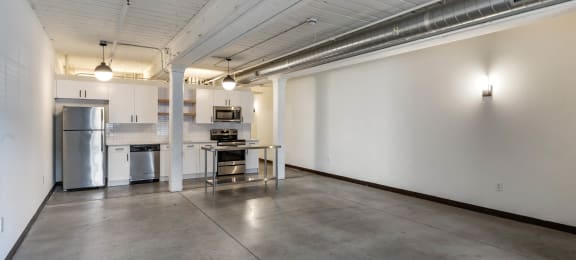 an empty room with a kitchen and a table in the middle at Highland Mill Lofts, Charlotte, North Carolina