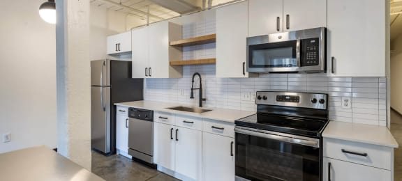 a kitchen with white cabinets and stainless steel appliances at Highland Mill Lofts, Charlotte