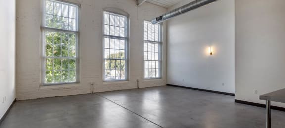 an empty room with three large windows and a table at Highland Mill Lofts, Charlotte, NC