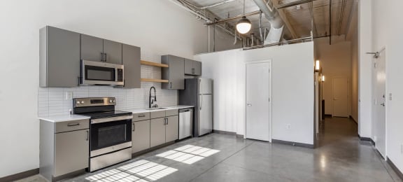 a kitchen with stainless steel appliances and white walls at Highland Mill Lofts, Charlotte