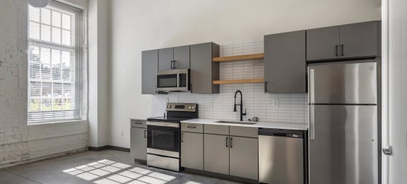 a kitchen with stainless steel appliances and a window at Highland Mill Lofts, Charlotte, North Carolina