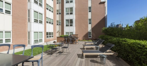 a large patio with tables and chairs in front of an apartment building at Amelia, Quincy, Massachusetts