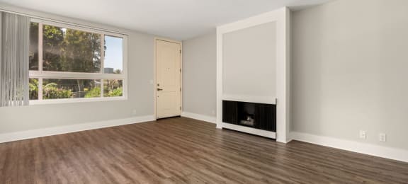 an empty living room with a fireplace and a large window