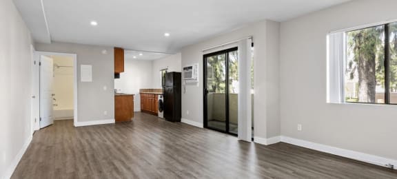 a living room with a hardwood floor and a door that leads to a kitchen