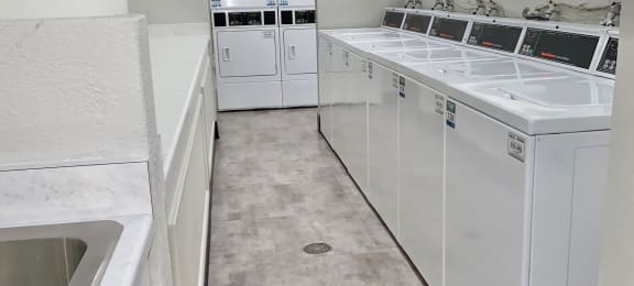 a large laundry room with white cabinets and appliances