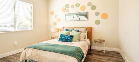 Model bedroom is furnished with a large bed and 2 nightstands at Village Greens of Queen Creek
