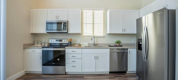 A kitchen with wood-style flooring and stainless steel appliances in an apartment at Village Greens of Queen Creek