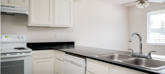 an empty kitchen with white cabinets and a stainless steel sink