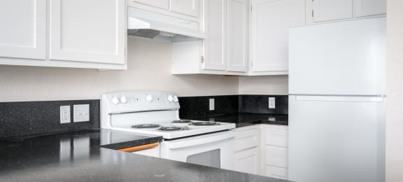 a kitchen with white appliances and black counter tops