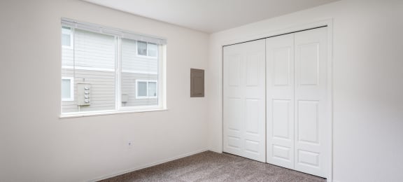 an empty room with carpet and a window and a closet