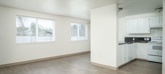 an empty kitchen and living room with white cabinets and white appliances