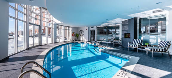 Curved indoor pool with floor to ceiling windows at La Voile Broisbriand apartments in Broisbriand, Quebec