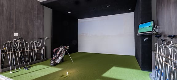 Indoor virtual golf simulator featuring large putting green at La Voile Pointe-Claire apartments in Pointe-Claire, Quebec