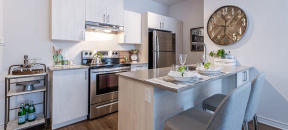 Modern kitchen with stainless steele appliances and quartz countertops at La Voile Pointe-Claire apartments