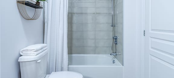 Modern white and grey bathroom featuring a shower tub at La Voile Pointe-Claire apartments in Pointe-Claire, Quebec