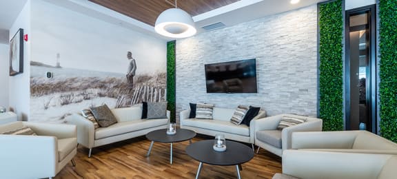 Spacious lounge seating social room with large screen TV at La Voile Pointe-Claire apartments in Point-Claire, Quebec