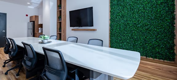 Conference room featuring large white central table and artificial living wall at La Voile Pointe-Claire apartments