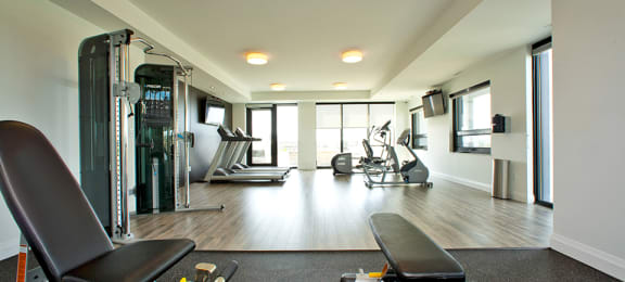 Gym with exercise equipment and windows, located in Building B at Trio on Belmont in Kitchener, ON