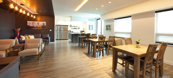 Penthouse resident's lounge with a large dining area with tables and chairs and a caterer's kitchen in the background at Trio on Belmont in Kitchener, ON