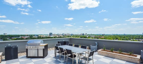 A rooftop patio with a BBQ grill and a table and chairs at Trio on Belmont in Kitchener, ON