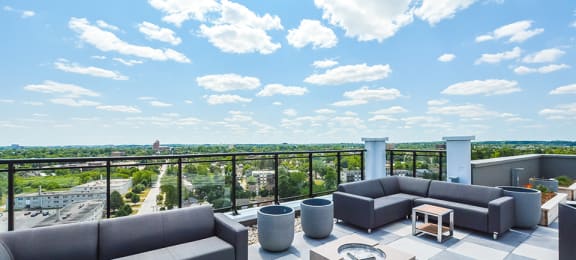 A rooftop patio with outdoor padded sectional couches and a view of the city at Trio on Belmont in Kitchener, ON