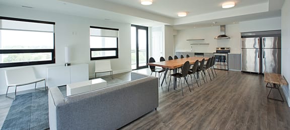 Social room with lounge area, large dining table and chairs and full kitchen located in Building C at Trio on Belmont in Kitchener, ON