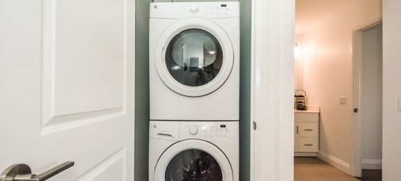 In-suite laundry with a white stacked washer and dryer in a 1 bed 1 bath variation B in building A at Trio on Belmont in Kitchener, ON