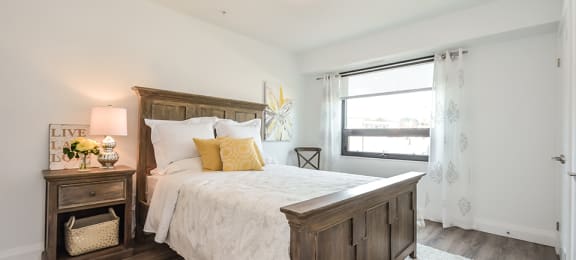 2nd bedroom with a large bed with wooden frame and window in a 2 bed + den 2 bath variation E in building A at Trio on Belmont in Kitchener, ON