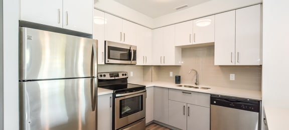 Kitchen with stainless steel appliances and white cabinets in a 2 bed + den 2 bath variation E in building A at Trio on Belmont in Kitchener, ON